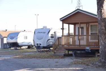 Three Stationary RVs Parked on Gravel Next to a Park Office at Council Road RV Park